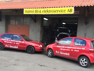 två röda lånebilar som står parkerade utanför Malmö Bil- och Elektroservice verkstad